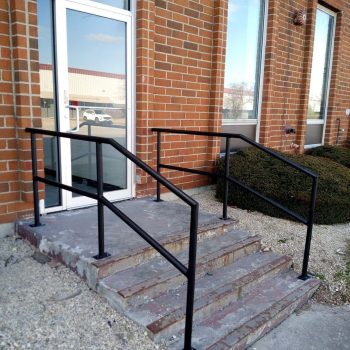 Black powder-coated metal railing beside brick steps