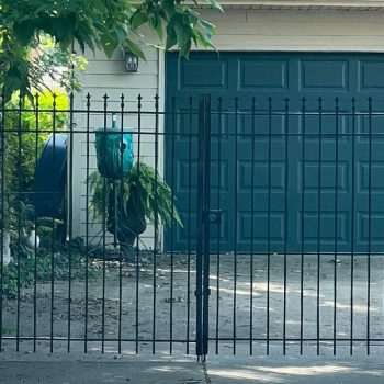 Metal gate and fence in front of a garage