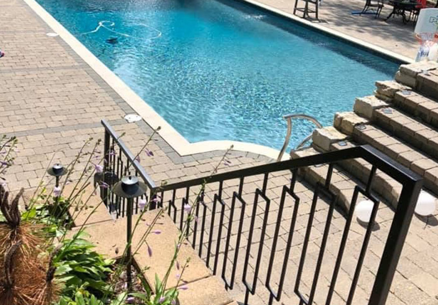 Exterior metal stair railing beside a swimming pool